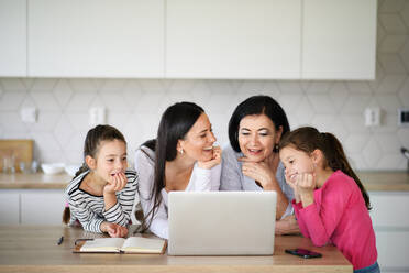 Glückliche kleine Mädchen mit einer Mutter und Großmutter zu Hause, die einen Laptop benutzen. - HPIF07567