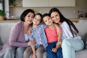 Portrait of happy small girls with mother and grandmother indoors at home, looking at camera. - HPIF07573