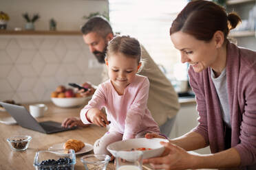 A family with small daughter indoors in kitchen, everyday life and home office with child concept. - HPIF07583