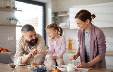 A family with small daughter indoors in kitchen, everyday life and home office with child concept. - HPIF07585