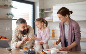 Eine Familie mit kleiner Tochter drinnen in der Küche, Alltag und Home Office mit Kinderkonzept. - HPIF07585