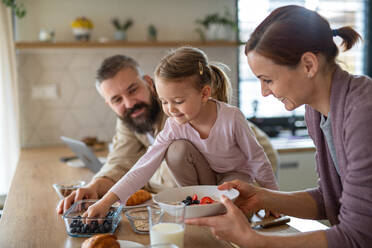 Eine Familie mit kleiner Tochter drinnen in der Küche, Alltag und Home Office mit Kinderkonzept. - HPIF07586