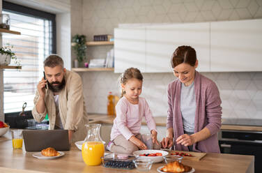 A family with small daughter indoors in kitchen, everyday life and home office with child concept. - HPIF07588