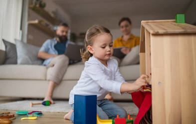 Ein kleines Mädchen spielt drinnen zu Hause, Alltag und Home Office mit Kind Konzept. - HPIF07605