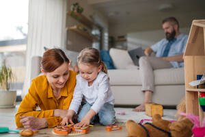 Eine Mutter mit kleiner Tochter spielt drinnen zu Hause, Alltag und Home Office mit Kind Konzept. - HPIF07606
