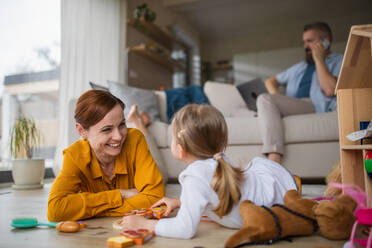 Eine Mutter mit kleiner Tochter spielt drinnen zu Hause, Alltag und Home Office mit Kind Konzept. - HPIF07607