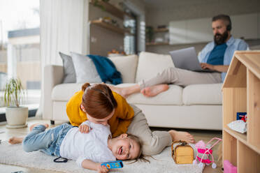 Eine Mutter mit kleiner Tochter spielt drinnen zu Hause, Alltag und Home Office mit Kind Konzept. - HPIF07609