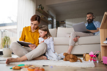 Eine Mutter mit einer kleinen Tochter, die ein Tablet zu Hause benutzt, Alltag und Home Office mit Kind Konzept. - HPIF07611