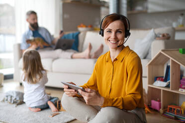 Geschäftsfrau mit Tablet und Headset arbeiten drinnen zu Hause, Alltag und Home-Office mit Kind Konzept. - HPIF07612