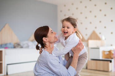 Eine glückliche Mutter mit ihrer kleinen Tochter, die lachend im Schlafzimmer spielt. - HPIF07633