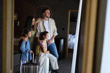 Eine glückliche junge Familie mit zwei Kindern, die ein Zimmer in einem Luxushotel beziehen, Sommerurlaub. - HPIF07643