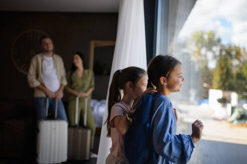 Eine glückliche junge Familie mit zwei Kindern und Gepäck im Zimmer eines Luxushotels, Sommerurlaub. - HPIF07644