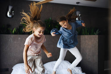 Zwei kleine Schwestern springen auf einem Bett in einem Hotel. - HPIF07651