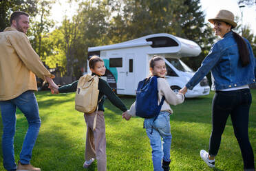Rückansicht einer jungen Familie mit Koffern auf dem Weg zum Wohnwagen im Außenbereich des Parks. - HPIF07658