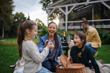 Eine glückliche junge Familie sitzt auf einer Decke und macht ein Picknick zum Mitnehmen im Freien in einem Restaurant. - HPIF07675