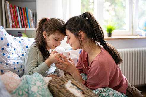 Portrait of mother looking after sick small daughter in bed at home. - HPIF07685