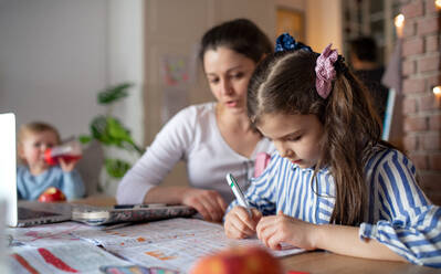 Portrait of mother with small daughter in kitchen, home schooling and distance learning concept. - HPIF07692