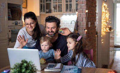 Glückliche Familie mit kleinen Töchtern in der Küche, Fernunterricht, Videogespräche mit der Familie oder Freunden. - HPIF07695