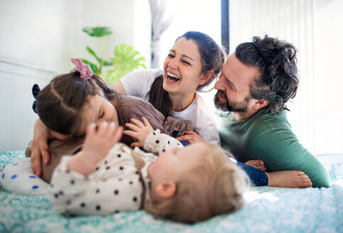 Portrait of happy family with two small daughters having fun on bed at home. - HPIF07701