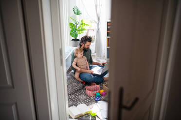 Beschäftigter Vater arbeitet mit kleinem Kleinkind Tochter im Schlafzimmer, Home-Office-Konzept. - HPIF07713