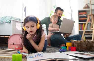 Beschäftigter Vater arbeitet mit kleinen Töchtern im Schlafzimmer, Home-Office-Konzept. - HPIF07714