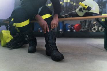 A lowsection of firefighter preparing for action in fire station at night - HPIF07724