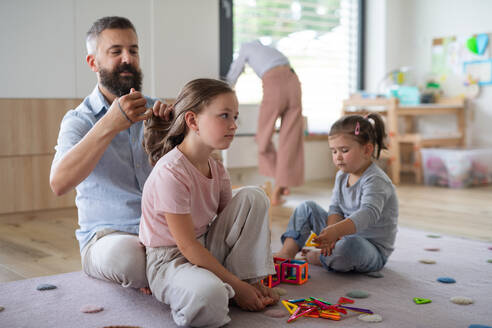 Ein Vater mit drei Töchtern, die zu Hause sind, spielen und sich die Haare machen. - HPIF07799
