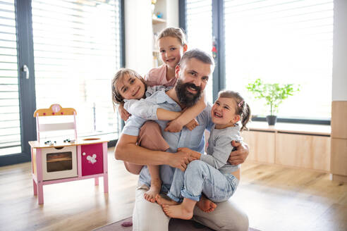 Ein Vater mit drei Töchtern zu Hause, der in die Kamera schaut. - HPIF07804