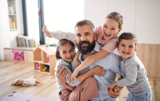 A father with three daughters indoors at home, looking at camera. - HPIF07807