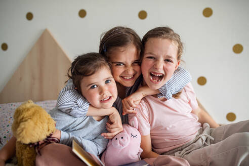 A portrait of three girls sisters indoors at home, looking at camera. - HPIF07812