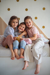 A portrait of three girls sisters indoors at home, looking at camera. - HPIF07813