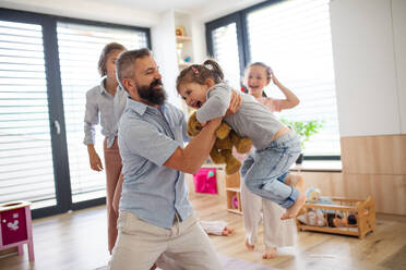 Ein Vater mit drei Töchtern, die zu Hause auf dem Boden spielen. - HPIF07815