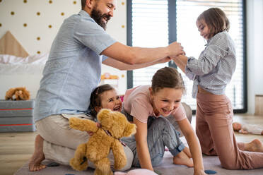 A father with three daughters indoors at home, playing on floor. - HPIF07823