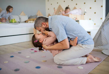 Ein Vater mit seinen Töchtern, die zu Hause spielen, lachen und Spaß haben. - HPIF07833