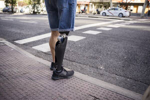 Man with prosthetic leg waiting at roadside - JJF00338