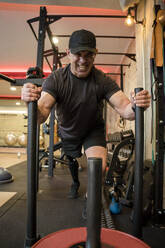 Entschlossener Mann mit Behinderung stemmt Gewichte im Fitnessstudio - JJF00357