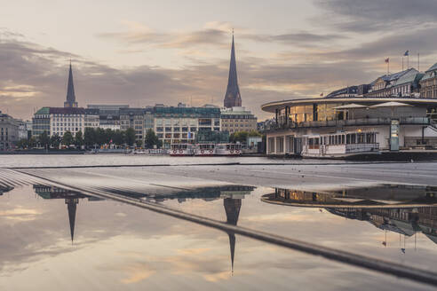 Germany, Hamburg, Church spires reflecting in street puddle at dawn - KEBF02612