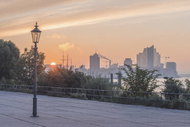 Deutschland, Hamburg, Einzelne Straßenlaterne im gepflasterten Bereich bei Sonnenuntergang stehend - KEBF02617