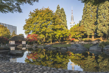 Germany, Hamburg, Japanese garden in Planten un Blomen park with Heinrich Hertz Tower visible in background - KEBF02626