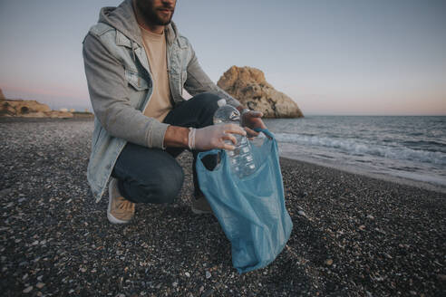 Mann sammelt Müll von der Küste am Strand - DMGF01040