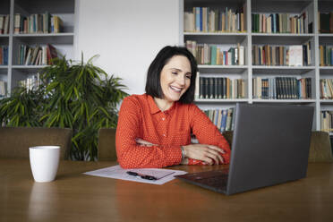 Happy businesswoman talking on video call through laptop - NJAF00244