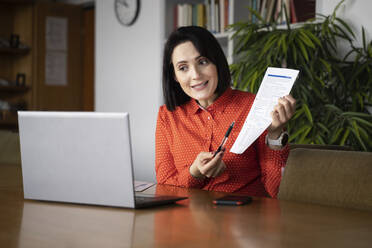 Geschäftsfrau, die ein Dokument per Videoanruf auf einem Laptop erklärt - NJAF00248