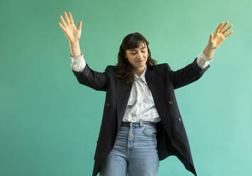 Young woman gesturing against green background - AXHF00296