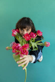 Young woman holding tulips standing on green background - AXHF00304