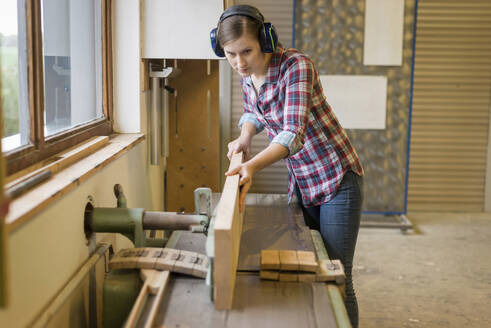 Engagierte Handwerkerin schneidet Holz in der Holzwerkstatt - PAF01977