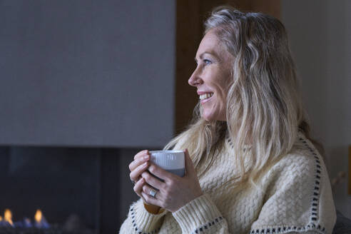 Happy woman with coffee cup at home - JAHF00184