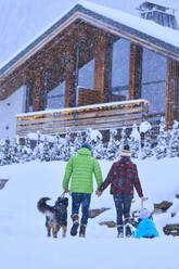 Parents with son and dog walking in snow - JAHF00189
