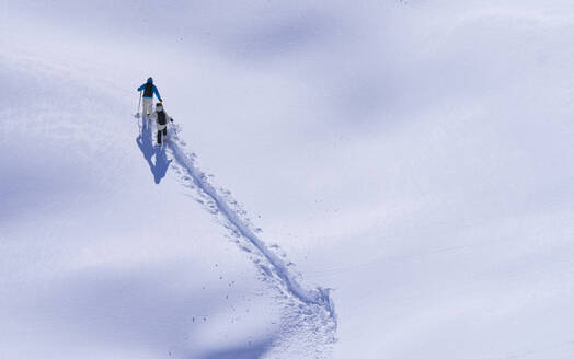 Man and woman with skies hiking on snowcapped mountain - JAHF00214