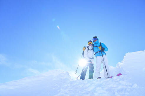 Loving mature couple standing in snow on sunny day - JAHF00228