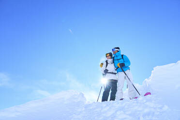 Loving couple standing in snow on sunny day - JAHF00229